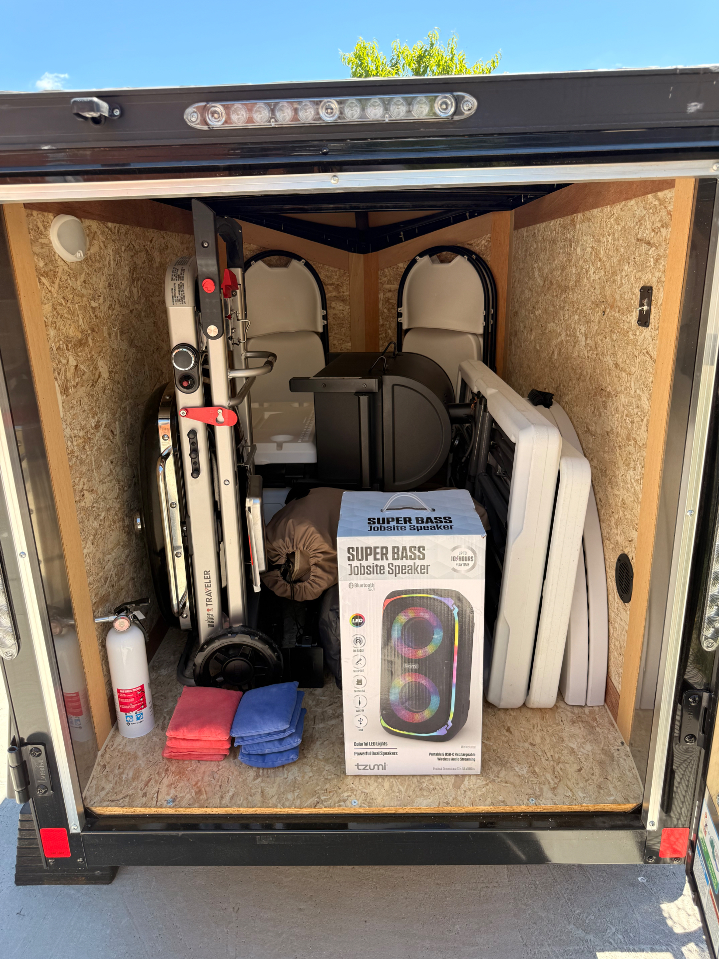 Inside the trailer: grill, folding chairs, tables, cornhole bags and Bluetooth speaker loaded and ready
